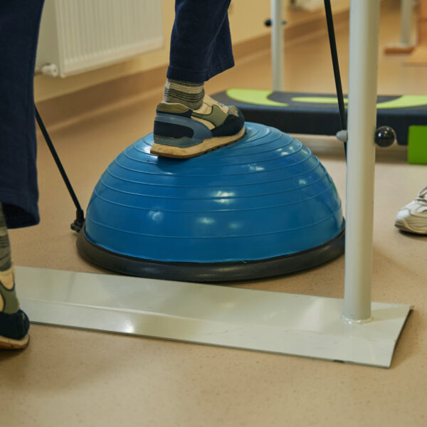 Cropped view on legs of stroke patient exercising on balance training platform during rehabilitation in clinic